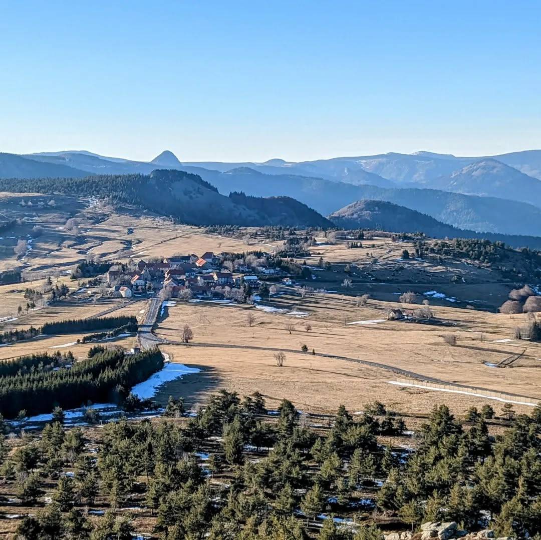 Depuis le suc du Montivernoux vers l'ouest, vue sur le village de Lachamp-Raphaël, la route départementale D122 qui mène vers le mont Gerbier de Jonc que l'on aperçoit distinctement